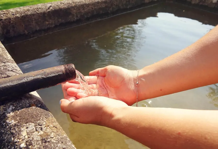 Hände im Wasser des alten Brunnens