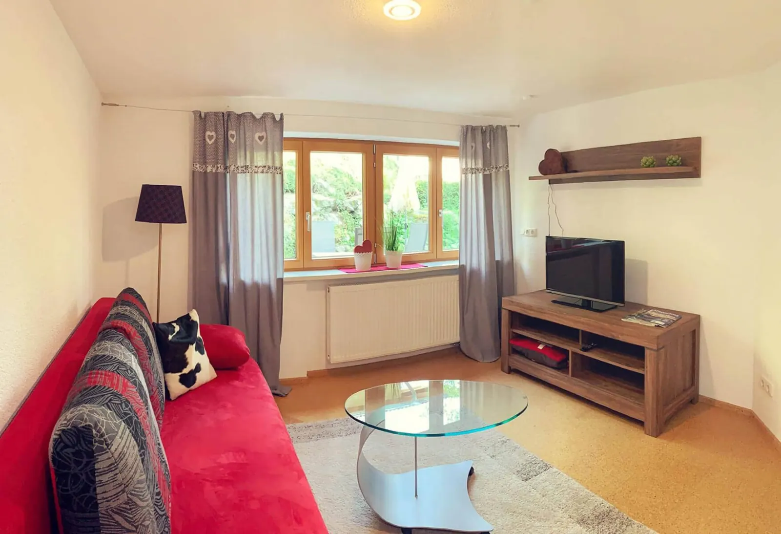 Wohnzimmer der Ferienwohnung Hompessen mit rotem Schlafsofa
