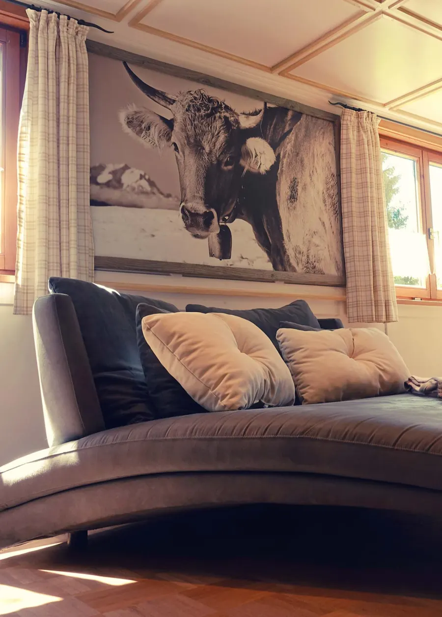Sofa in der Stube vor einem Bild mit Allgäuer Kuh