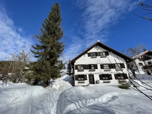 Das Bauernhaus im Schnee unter blauem Himmel